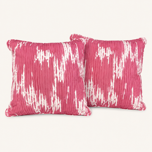 Pair of pink and ivory abstract decorative pillows on a warm white background