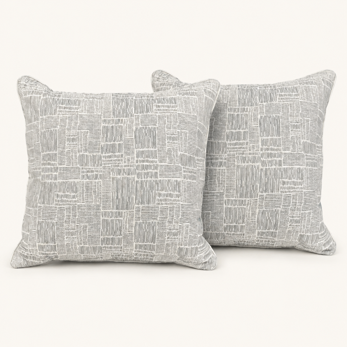 Pair of textured grey and ivory geometric pillows on a warm white background