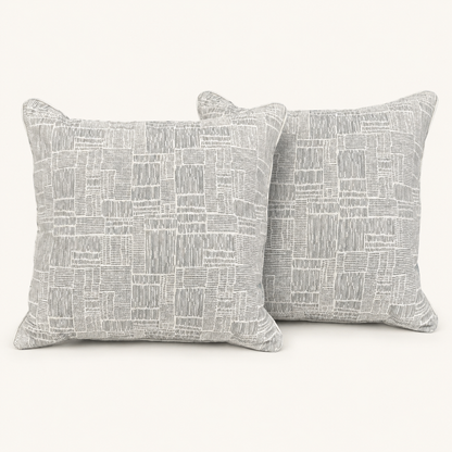 Pair of textured grey and ivory geometric pillows on a warm white background