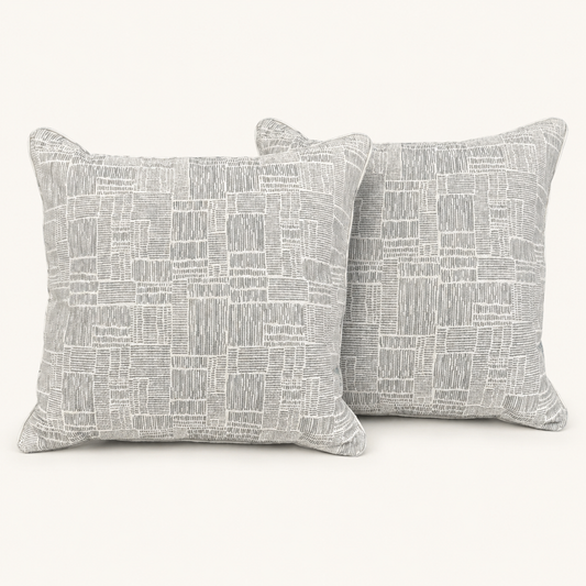 Pair of textured grey and ivory geometric pillows on a warm white background